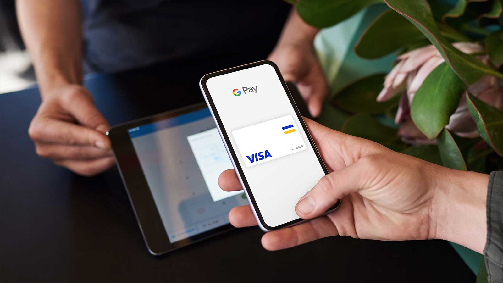 A person holding his phone in front of a tablet ready to pay with Google Pay. 