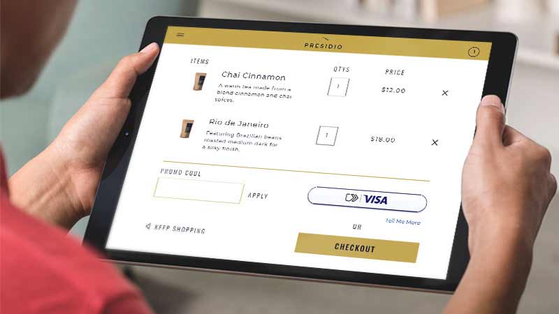 An individual using a tablet to make a payment for coffee, utilizing the convenience of Visa Click to Pay payments. 